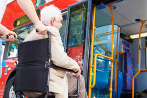 Man is assisted as he boards the bus in a wheelchair