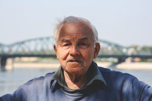 Older man near river with bridge