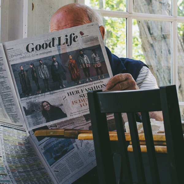 Older man reads the newspaper in his kitchen