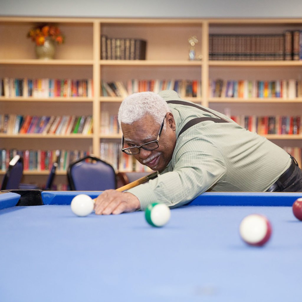 Older man, named Chuck, playing a game of pool