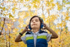 Young Boy Listening to Music in the Woods