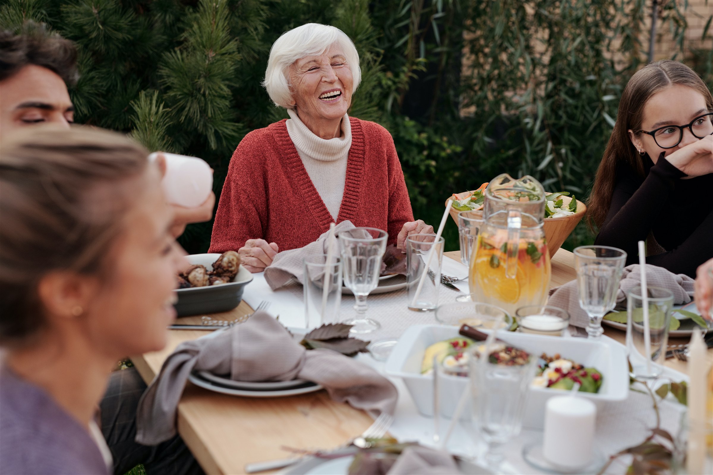 older woman sitting at dinner table with younger family members