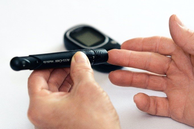 Person's hands checking their blood sugar with a finger prick