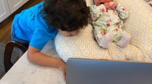 Toddler and baby on cushion looking at a computer