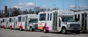 A line of MARTA Reach Shuttles, with pink and orange logos emblazed on their sides, stands ready in a parking lot.