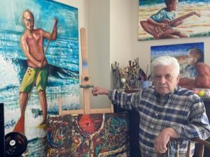 Salvador sits in his art studio among his easles and finished paintings. 