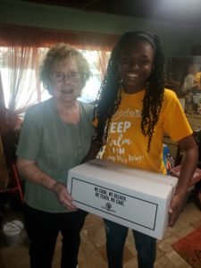 Older white woman standing next to a younger black woman holding a meal delivery box box